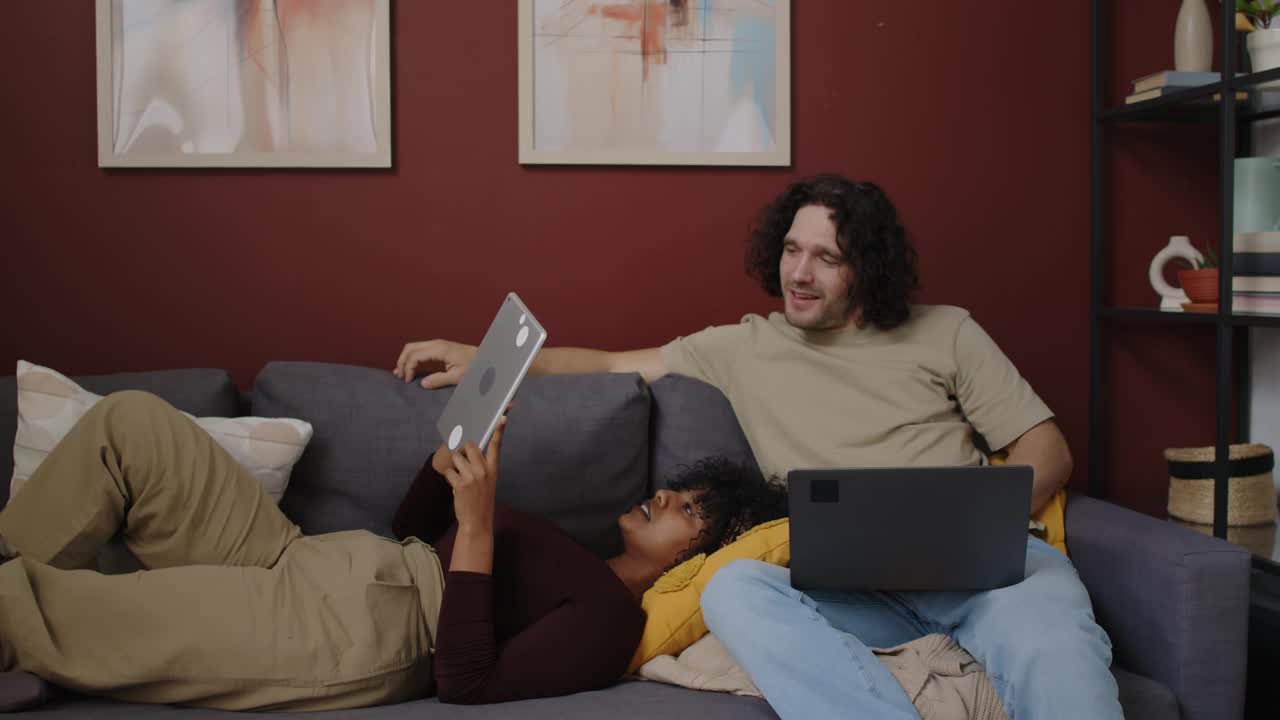不同种族的情侣一起坐在家里的沙发上视频下载
