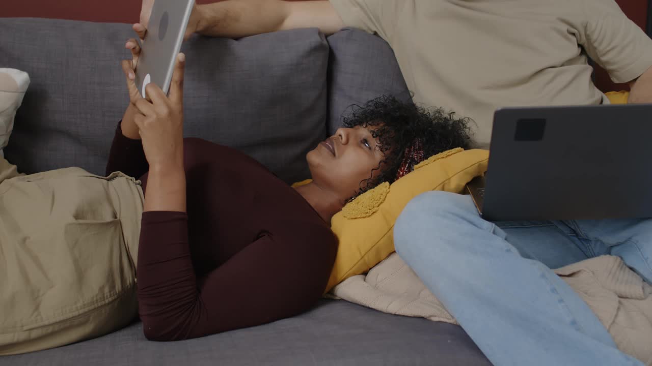 跨种族夫妇在家休息时在平板电脑上浏览视频下载