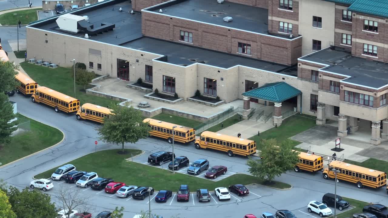 一所大型高中，校车排起长队等待下课。航拍拍摄。视频下载