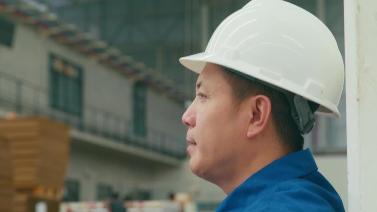 专业的亚洲男性工业工程师在制造工厂脱下头盔。在制造厂或生产厂工作。视频下载