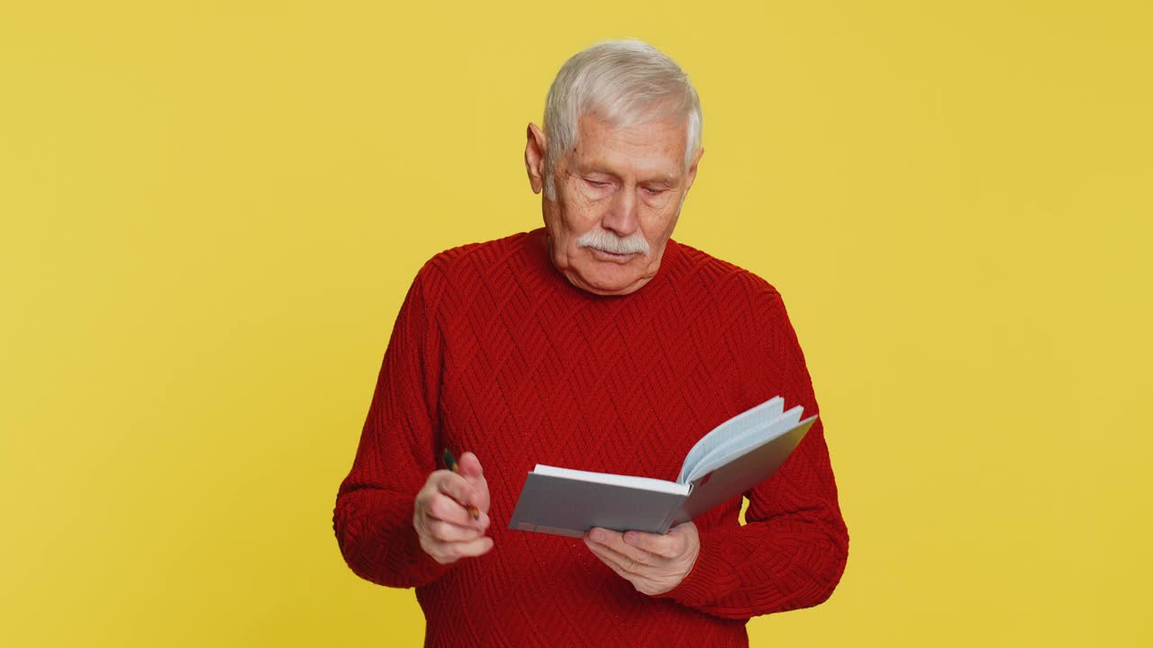深思熟虑的老人做笔记，用笔把自己的想法写进记事本，记下好主意视频下载