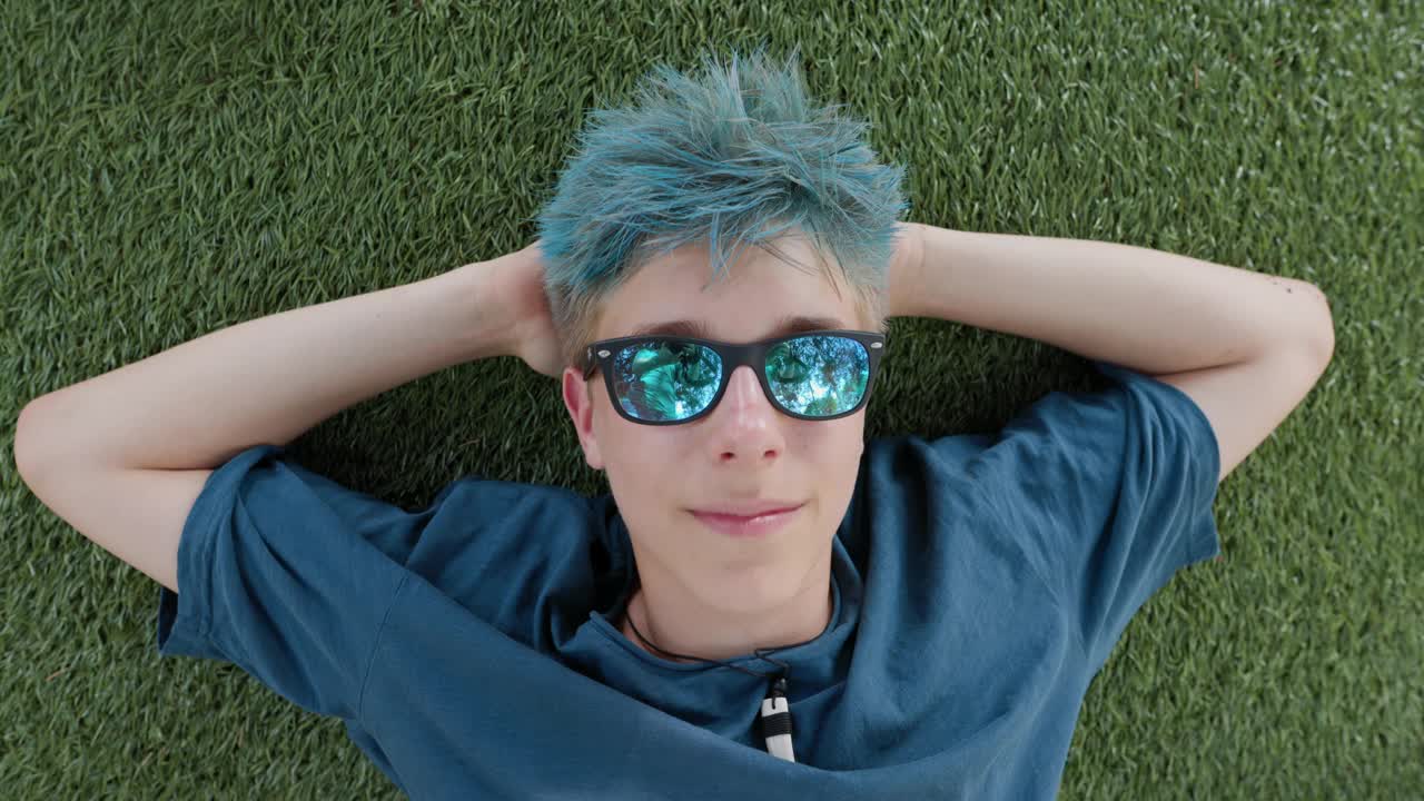 一个十几岁的男孩躺在人造草坪上的肖像视频下载