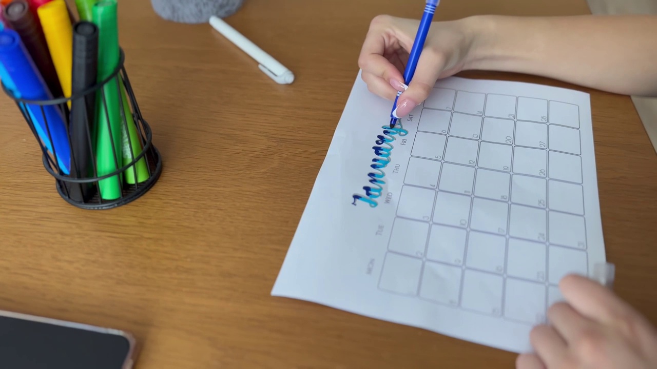 一个女人用蓝色记号笔在日历上写下一月这个词视频下载