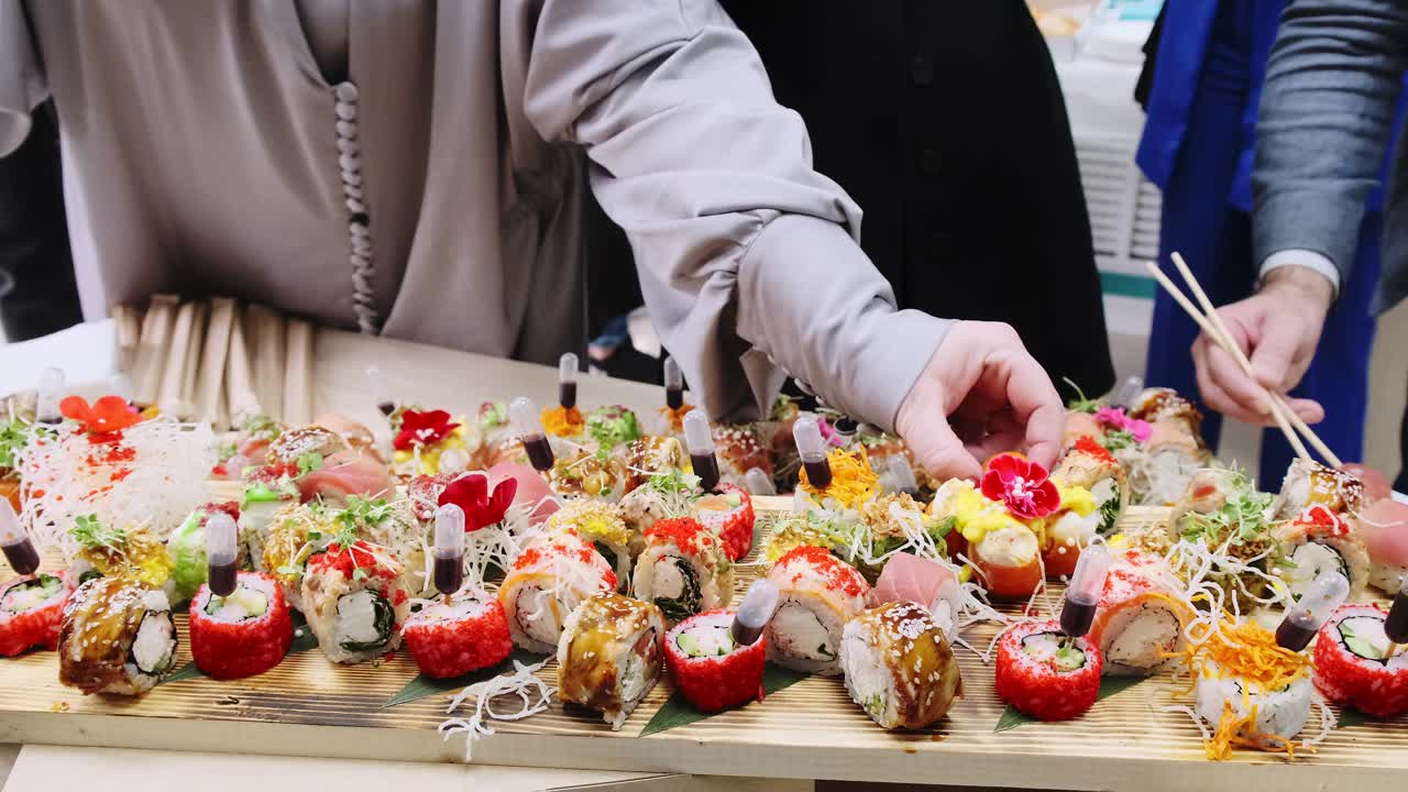日本寿司。一套漂亮的寿司卷放在木板上。活动前的自助餐。人们吃寿司视频下载