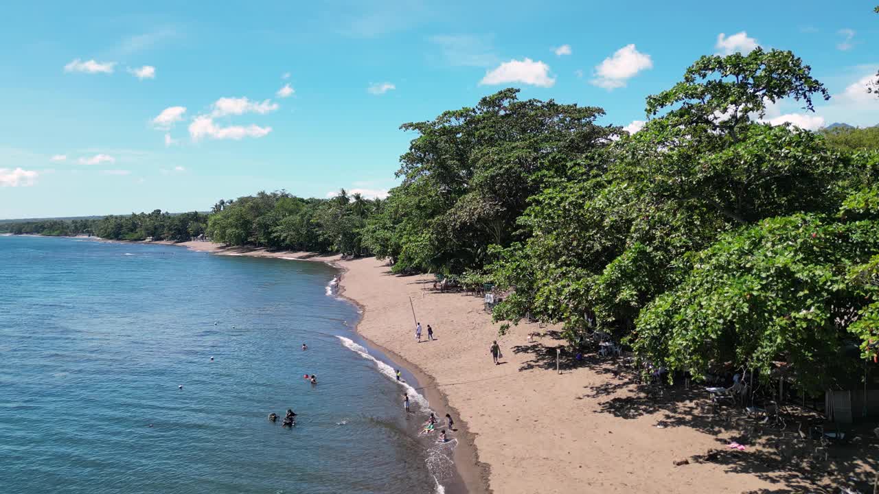 在热带岛屿上，海浪拍打着沙滩和游客视频下载