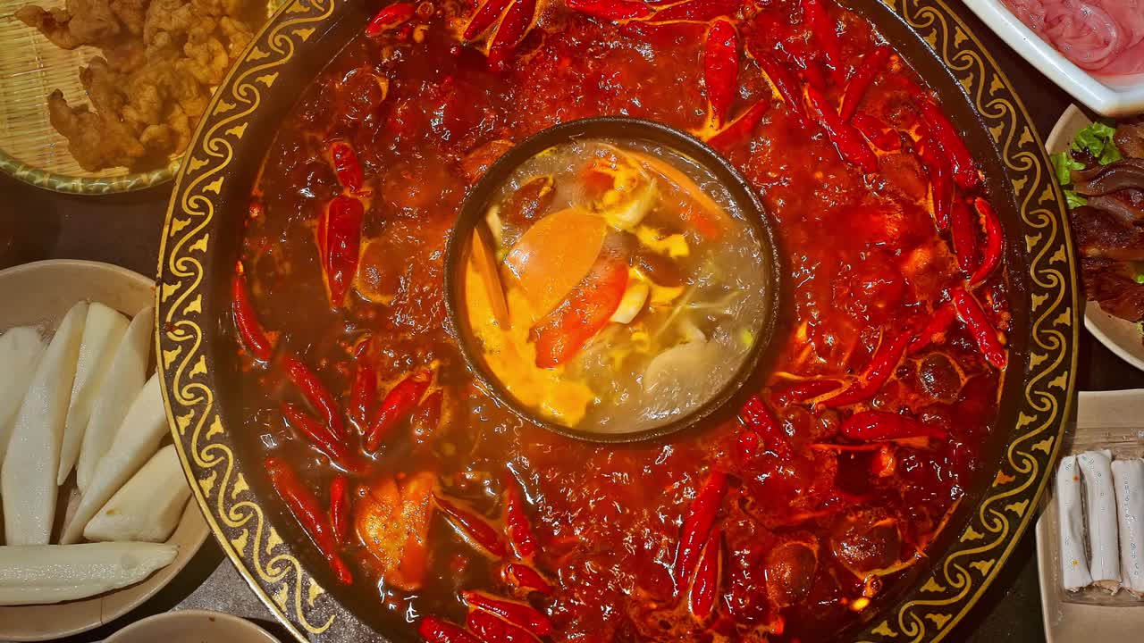 中国的麻辣火锅。一层红辣椒漂浮在沸腾的火锅底。视频下载