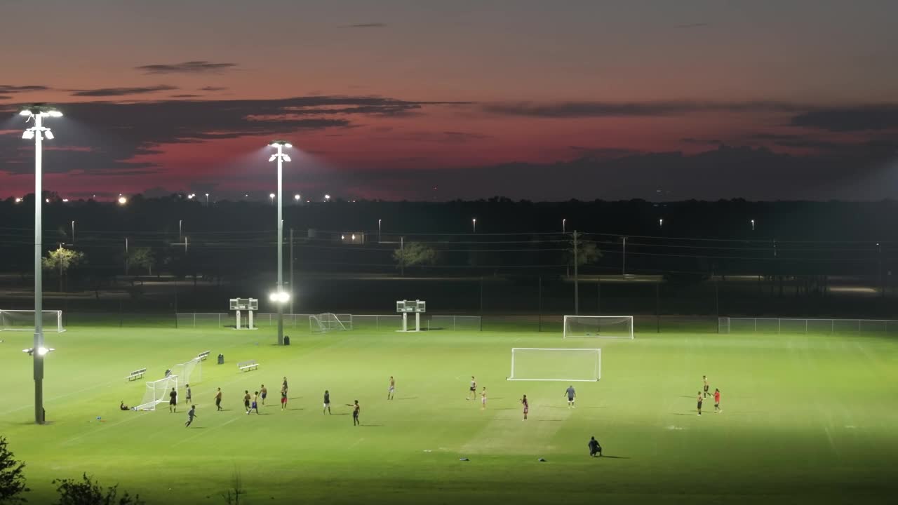 夜晚，人们在灯火通明的公共体育场里踢足球。积极的生活方式理念视频下载