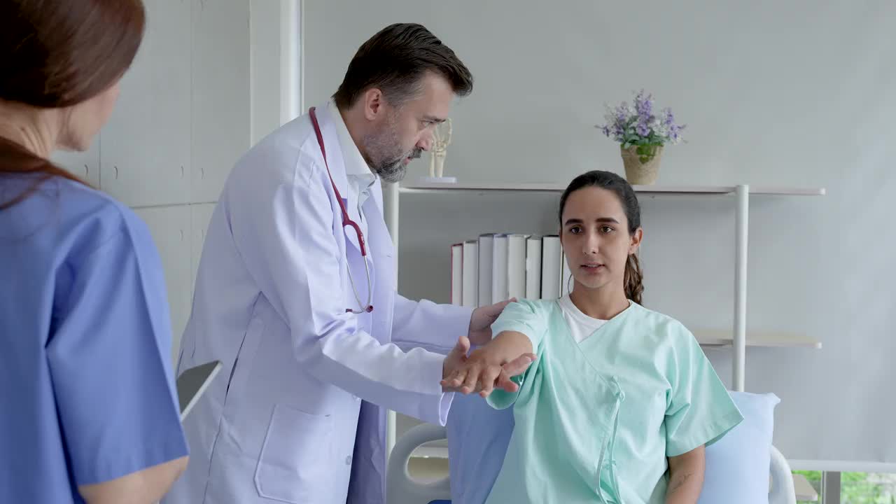 混血中年男医生举着女病人站在平板上记录护士进一步检查的治疗过程。视频素材