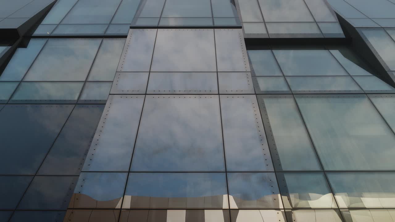 云层反射在现代办公大楼的大玻璃窗上，底部视图视频下载
