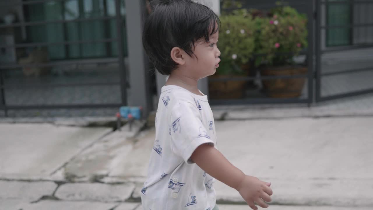 快乐的亚洲男孩在家里走来走去。探索周围的事物。视频下载