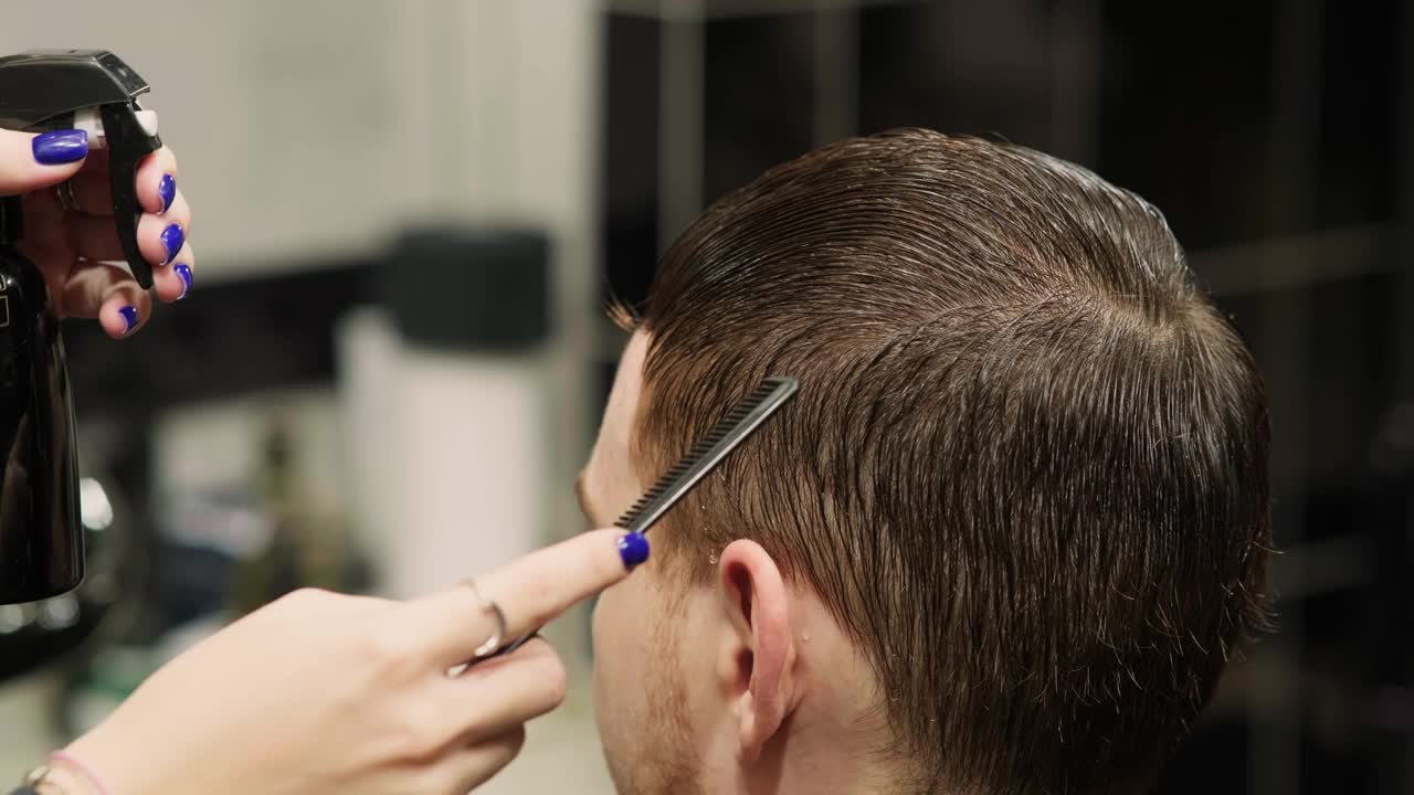 时髦的理发师在理发店给一个男人理发。男士的发型和理发在沙龙。用修剪器护理头发。理发师在一家复古理发店理发。视频下载