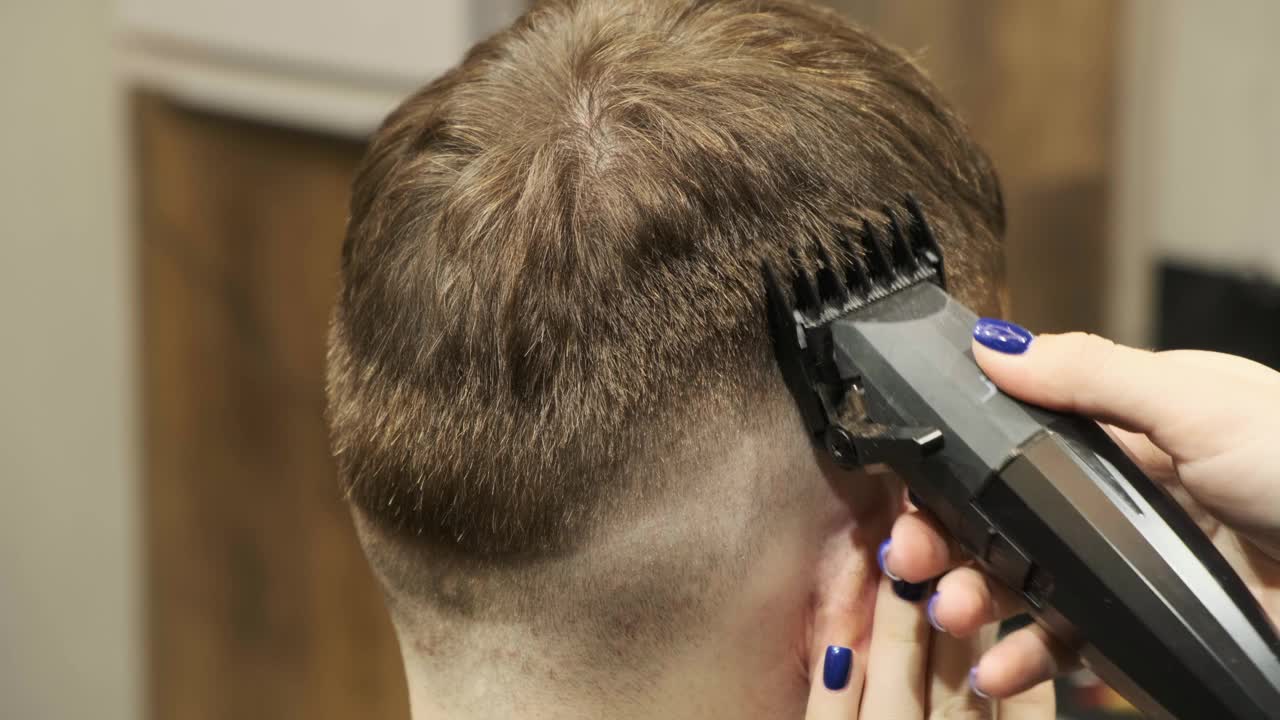 时髦的理发师在理发店给一个男人理发。男士的发型和理发在沙龙。用修剪器护理头发。理发师在一家复古理发店理发。视频下载