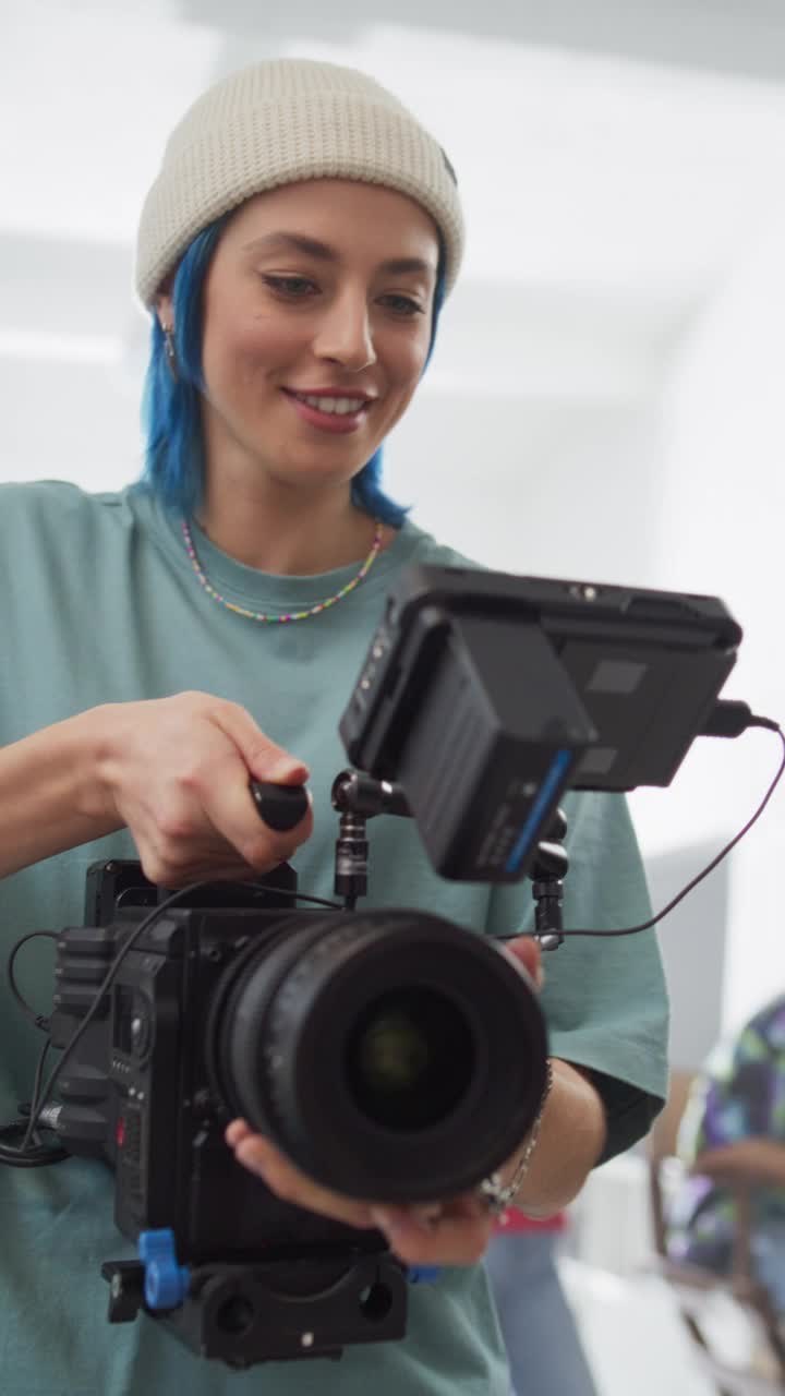 垂直屏幕:慢动作拍摄的女摄影师在拍摄设置，使用数码相机拍摄高质量的镜头为电影项目。操作相机的创意女性视频下载