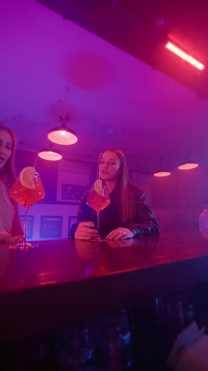 两个快乐的女性朋友在霓虹灯下的酒吧聊天视频下载