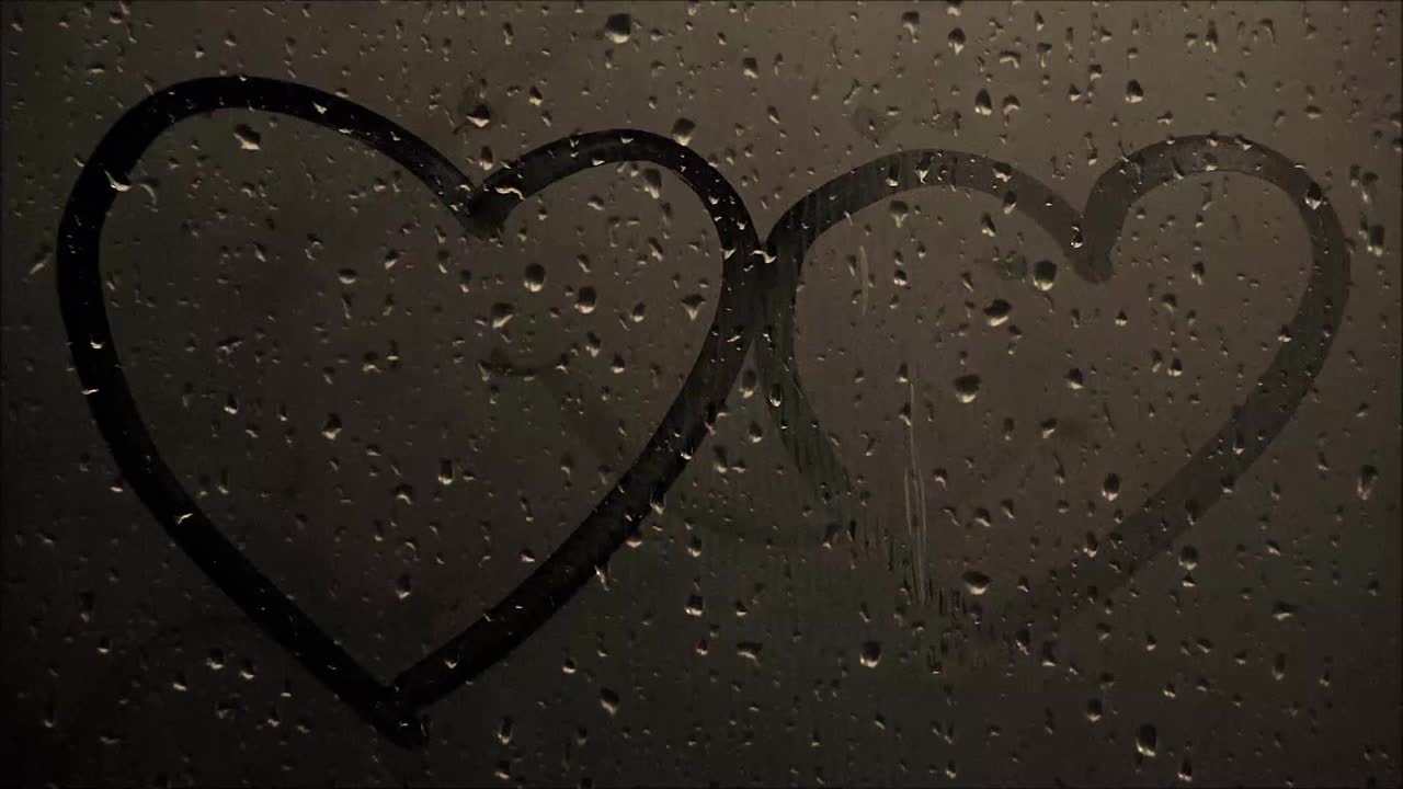 下雨天窗户玻璃上手写的一对心的镜头视频下载