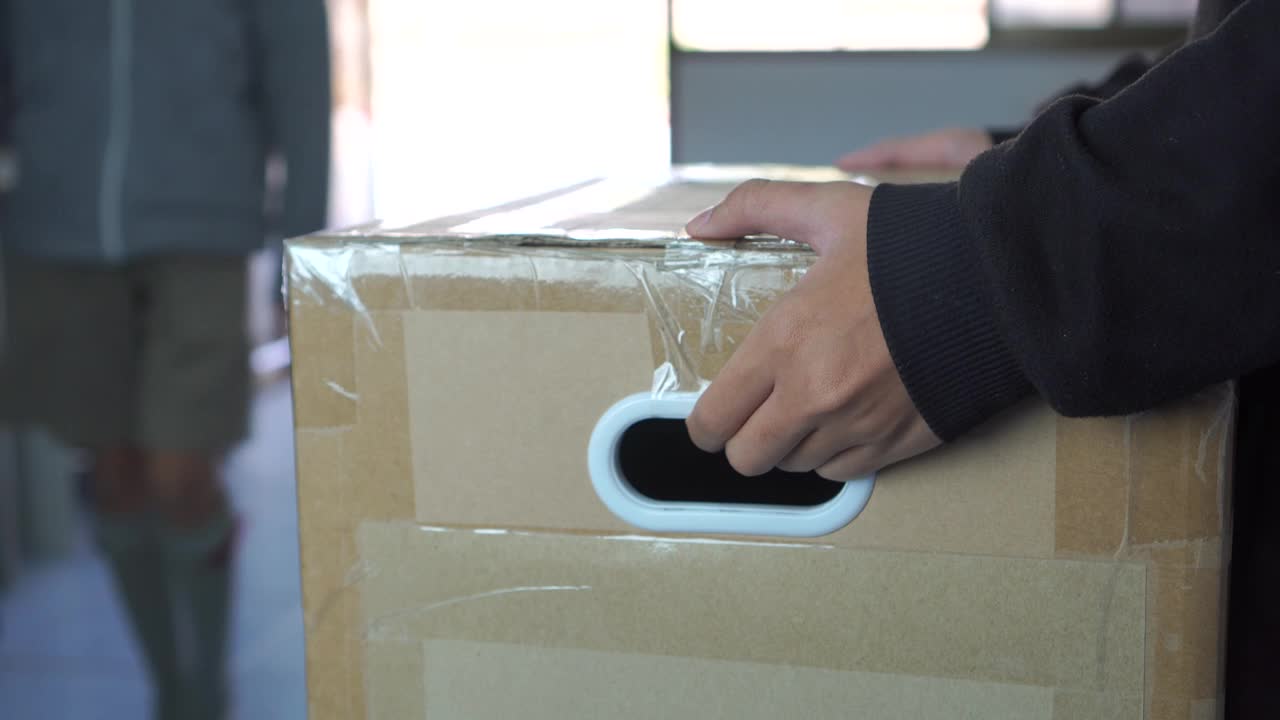 手信使或快递员拿着包裹箱包裹交付客户。送货员，送货员携带有复印空间的纸板的详细情况。在线航运快递概念视频素材