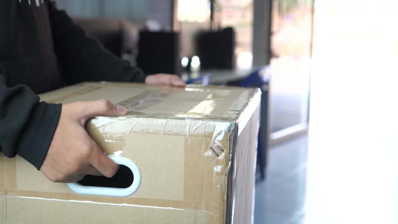信使或快递员携带包裹箱将包裹送到客户家中。送货服务快递员，送货员从网上送货快递员携带纸板的详细信息视频素材