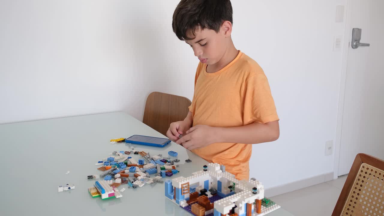 10岁的巴西孩子穿着橙色睡衣，在玩积木。视频下载