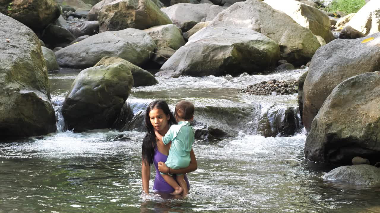 带着小婴儿的妇女从河中出来，撞上了大石头视频下载