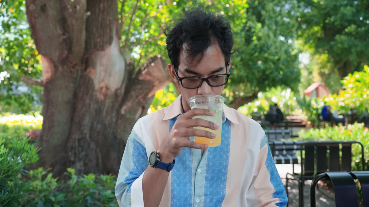 亚洲中年男性饮用加冰块的冰苏打水后出现牙齿健康问题。一名男子在咖啡馆喝了一口加冰的冷苏打水后，牙齿剧烈疼痛。牙齿健康和护理，牙齿问题的概念。视频下载