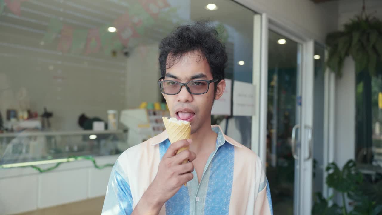 不健康的牙齿敏感的亚洲人在吃冰淇淋或冷甜点时使用小勺子来避免牙痛。中年男子戴眼镜，表现出严重的牙痛、牙齿敏感、蛀牙。牙龈萎缩，牙病视频下载