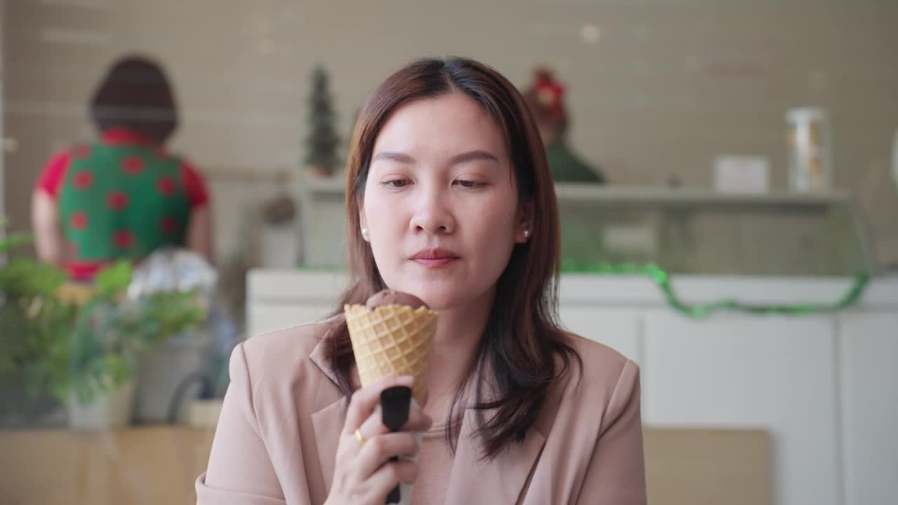 中年成年亚洲妇女拿着美味的冰淇淋和小勺子，吃了冷甜点后没有用勺子就牙痛。吃了冰淇淋后牙齿敏感的亚洲女性。牙龈萎缩，牙齿护理。视频下载