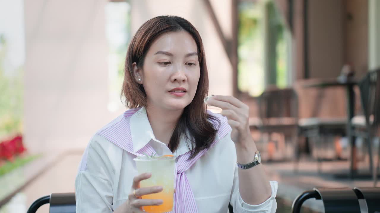 有牙齿健康问题的亚洲女性。
一名中年亚洲妇女在一家咖啡馆喝了一口加冰的冷苏打水后，牙痛得厉害。不幸的女孩喝了冷饮后，虽然使用吸管，但仍感到牙齿疼痛。视频下载