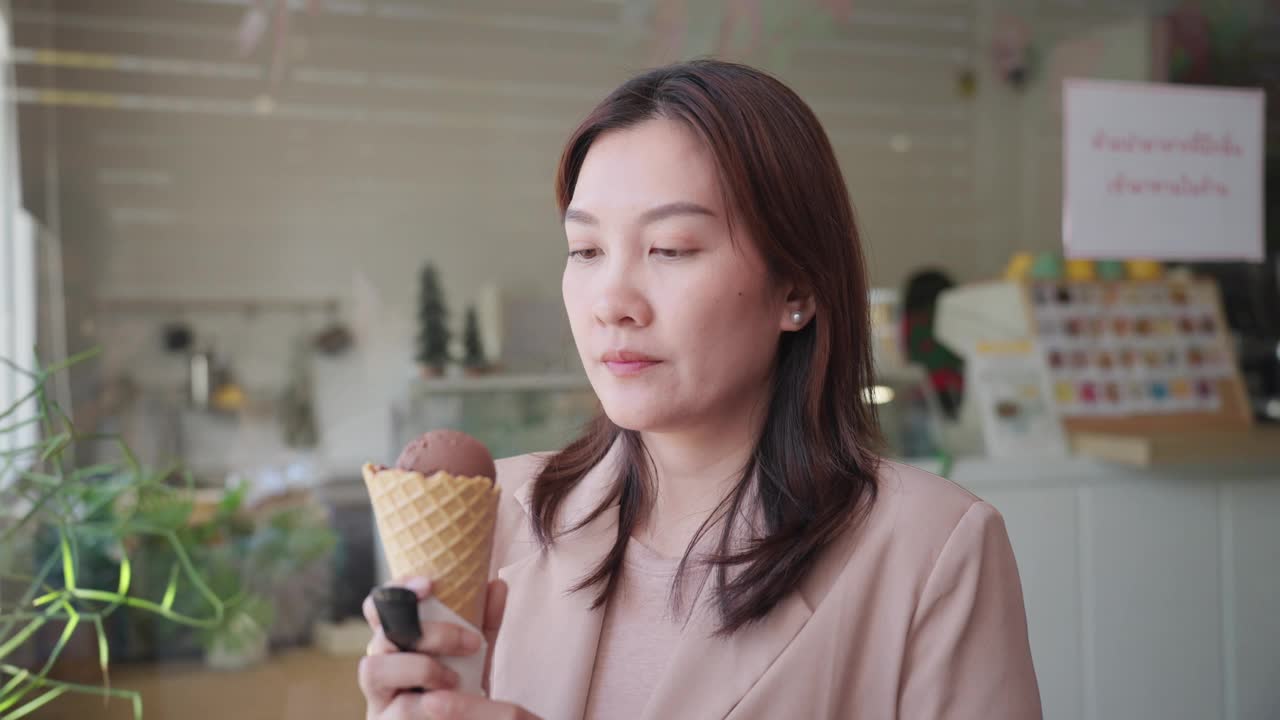 亚洲中年女性喜欢去咖啡馆买美味的冰淇淋，但吃完冰尖叫后，她感到牙痛和疼痛。美丽的亚洲女人在吃冷甜点时牙齿敏感。牙龈萎缩，牙齿护理。视频下载