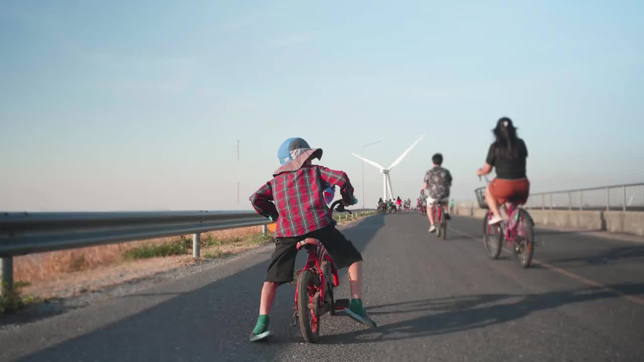 快乐男孩在风力涡轮机前骑车。视频下载