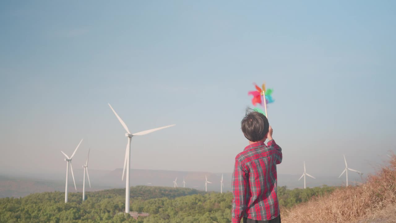 快乐的男孩旋转风车玩具与风力涡轮机。视频下载