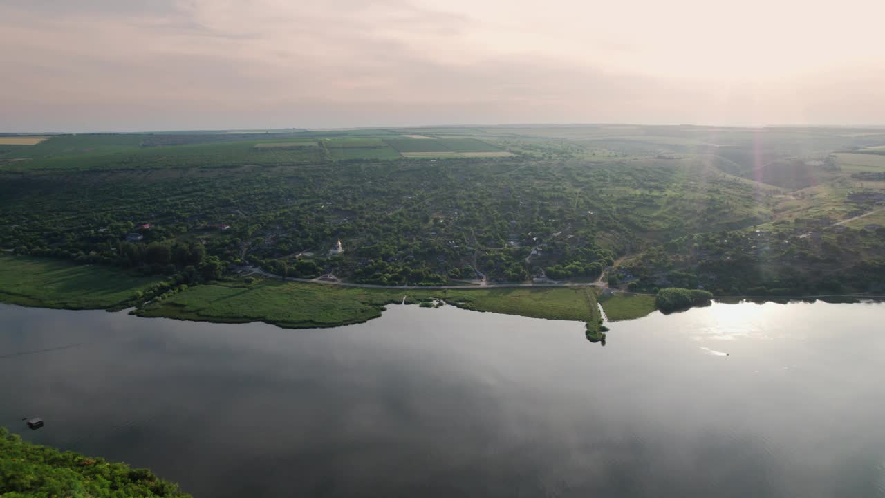 无人机在童话般的村庄上空飞行，德涅斯特河岸边有一座白色的教堂。摩尔多瓦共和国。视频下载