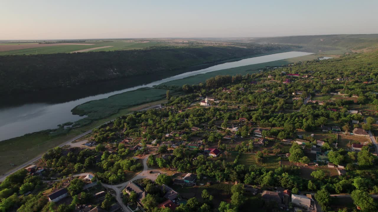 无人机在童话般的村庄上空飞行，德涅斯特河岸边有一座白色的教堂。摩尔多瓦共和国。视频下载