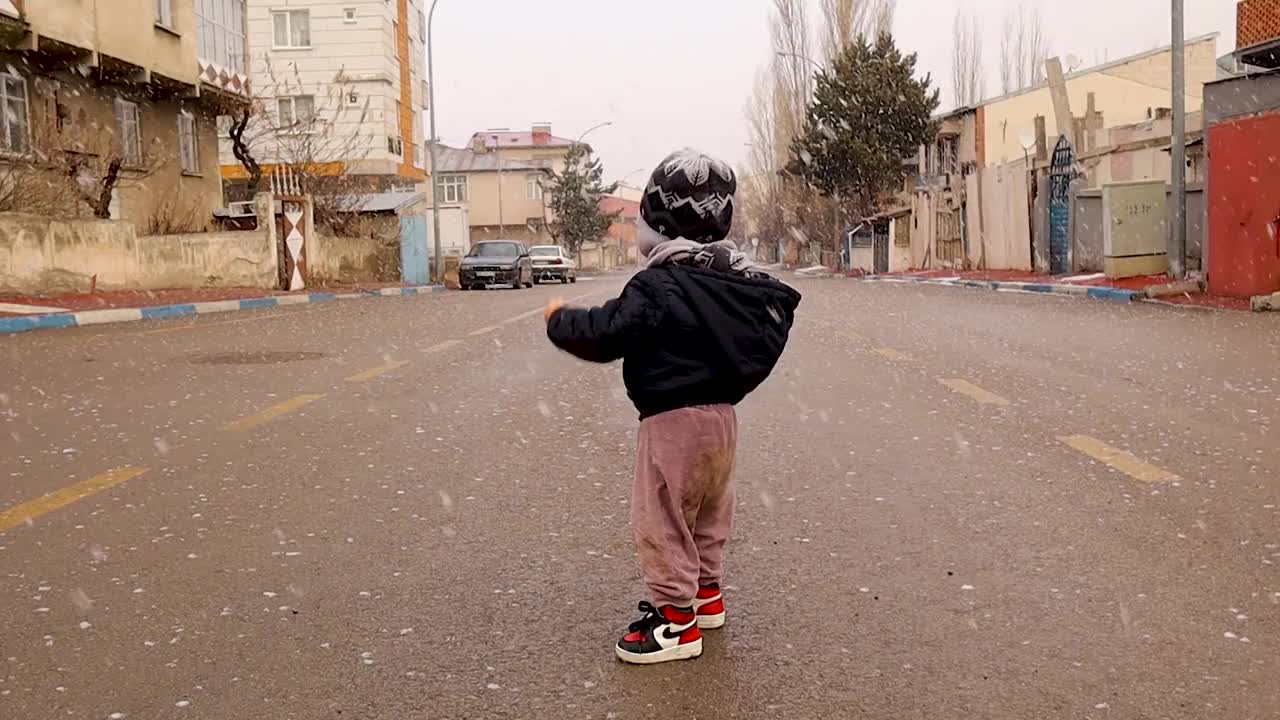 在土耳其埃尔祖鲁姆的街道上，宝宝对飘落的雪花很开心。美好的童年，宝贝。孩子们玩得很开心。视频下载