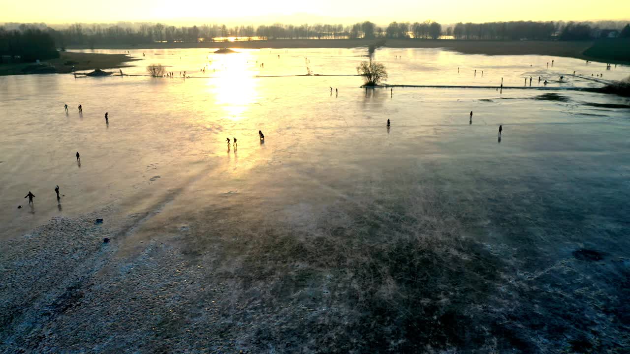 冰湖上的溜冰者。冬日的夕阳。无人机飞过浪漫的风景。视频下载