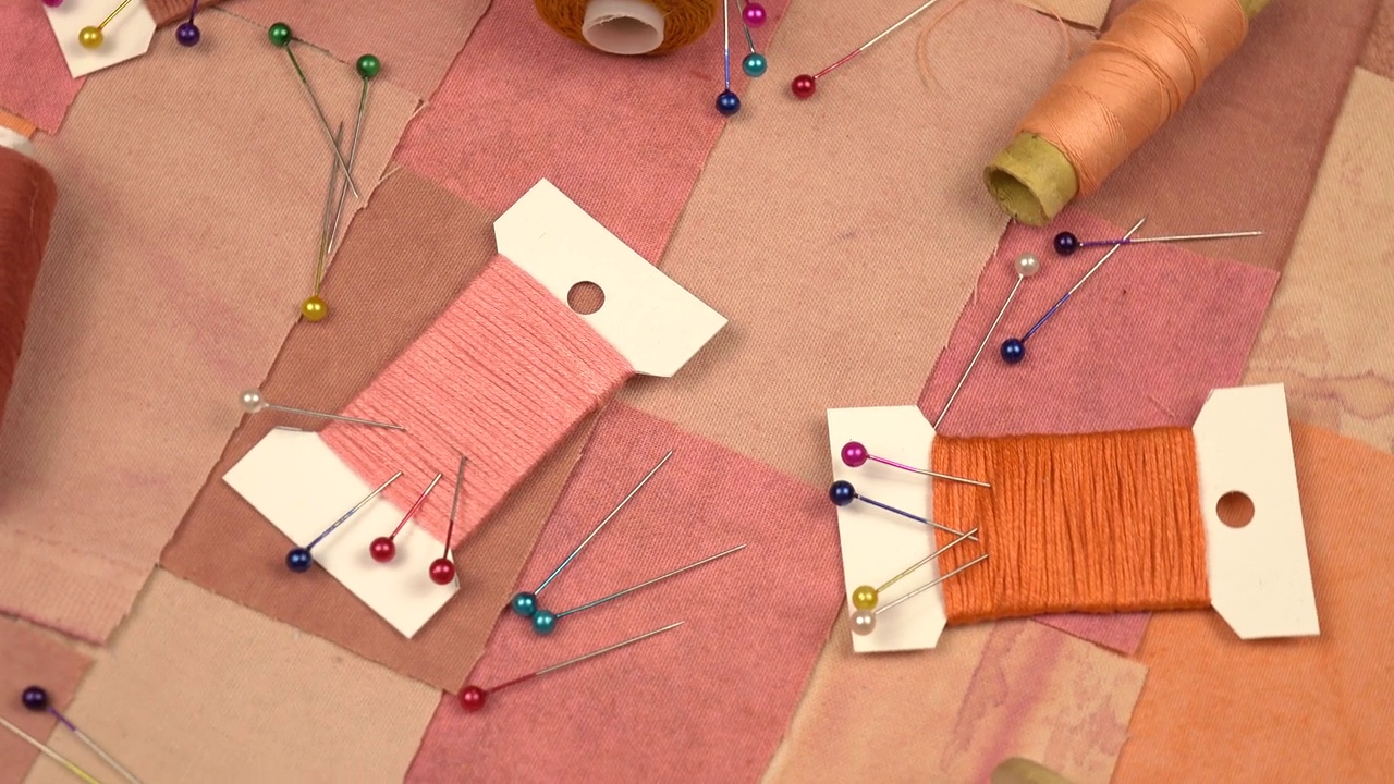 用于拼接缝纫的配件放在粉红色和棕色调的拼接纺织品上视频素材