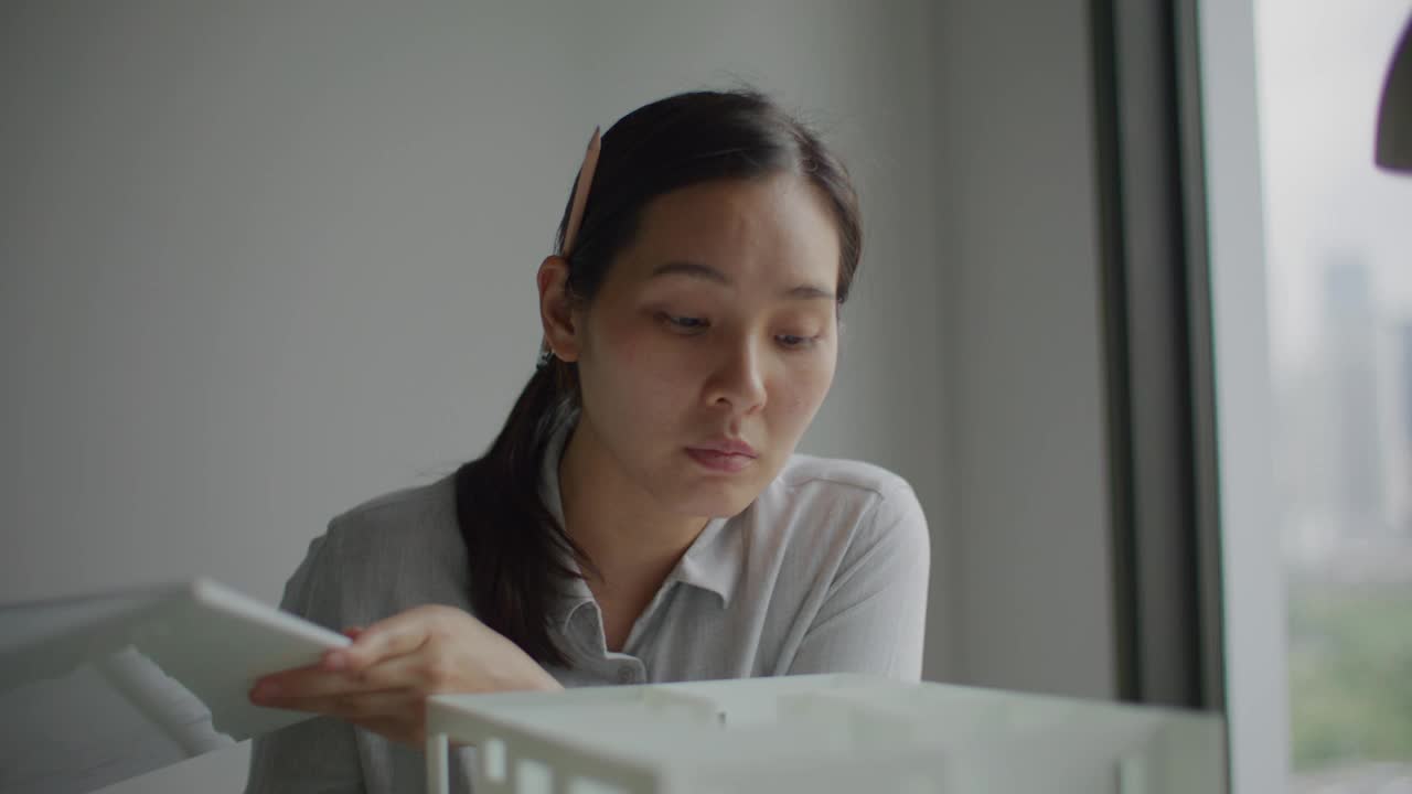 亚洲建筑师一边看一边检查房子模型视频素材