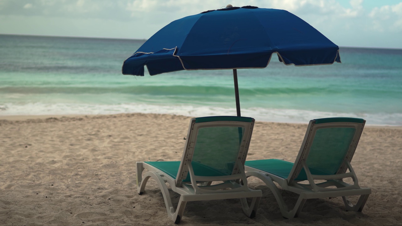 宁静的海滩场景:两把空椅子和一把伞，俯瞰大海视频下载