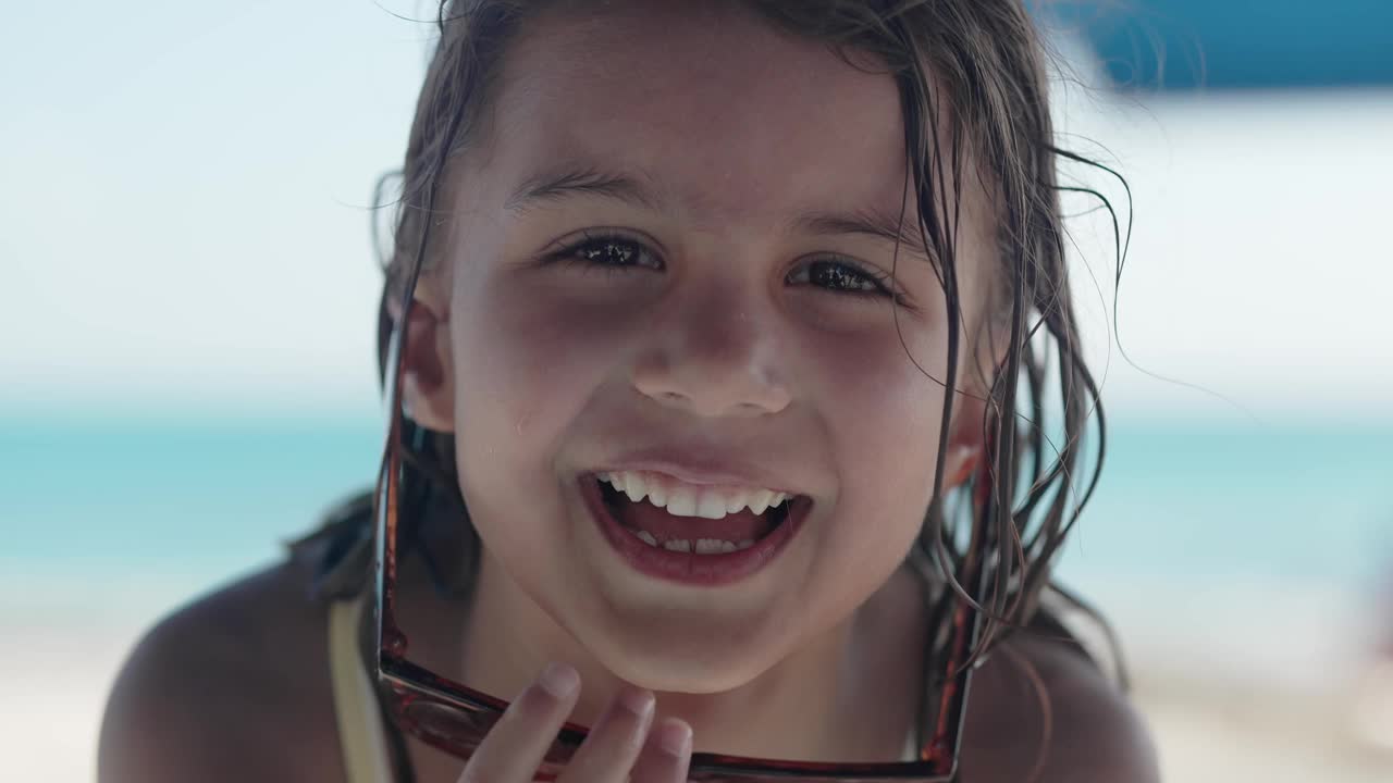 海滩乐趣:快乐的5岁女孩在海边微笑视频下载