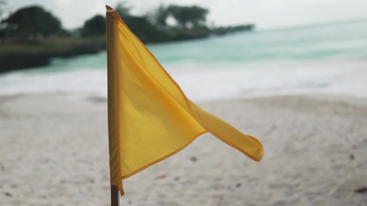 游泳风险自负:黄旗在海滩与波浪背景视频下载