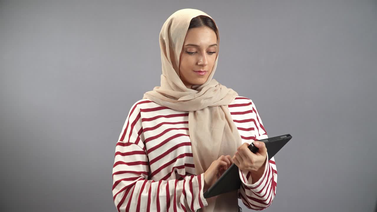 漂亮的年轻伊斯兰妇女特写，伊斯兰妇女使用平板电脑视频下载