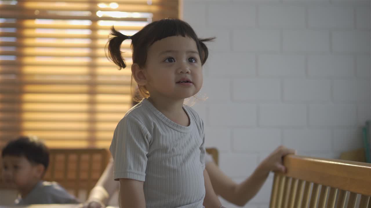 可爱的亚洲女婴攀爬，试图达到高桌上的东西视频下载