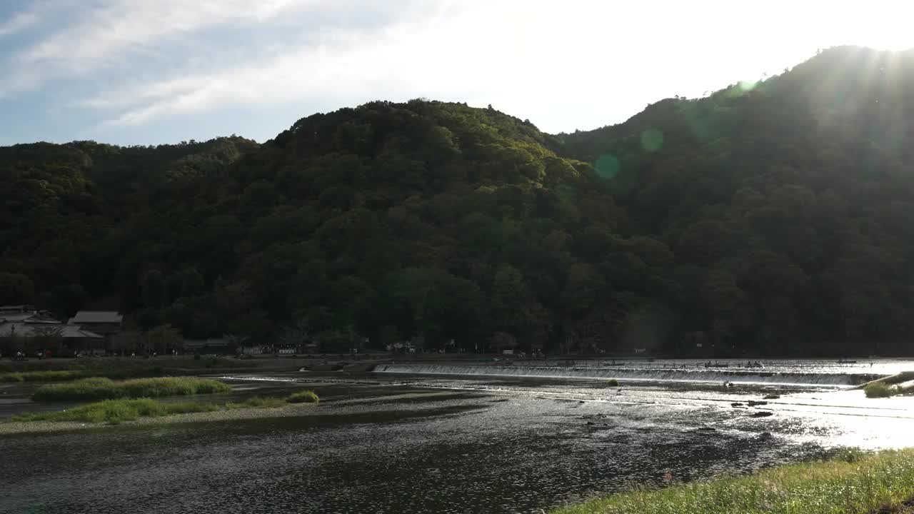 风景优美的桂川河在京都岚山的森林山坡上流动，镜头光晕在镜头中。建立视频下载