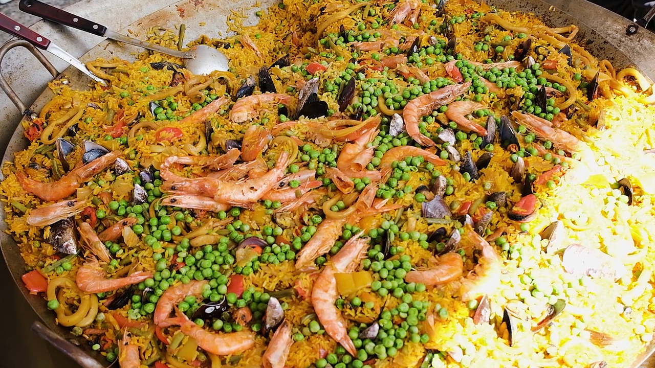 墨西哥海鲜饭用几种材料(大米，虾，豌豆，贝类和西红柿)在一个大锅里做。视频下载