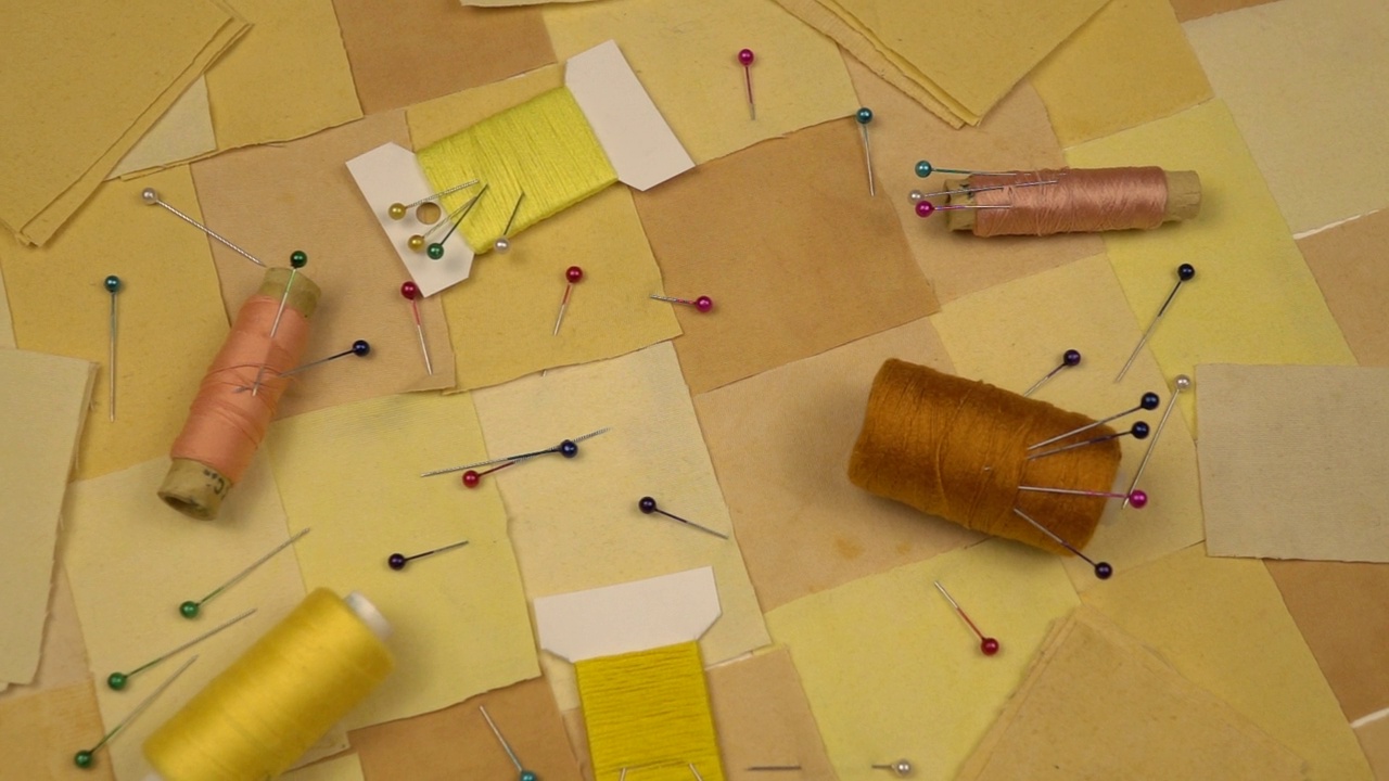 拼接缝纫的配件躺在拼接纺织品上，黄色调，慢动作视频素材