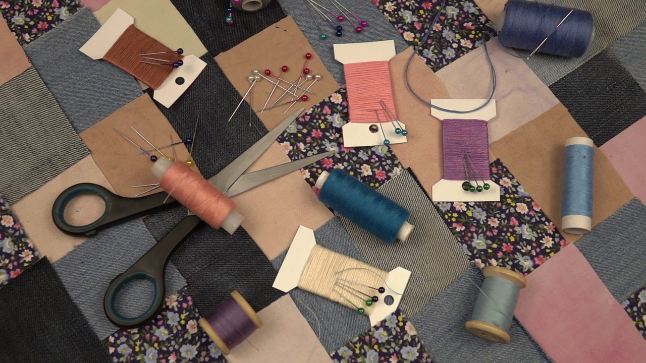 拼接缝纫的配件放在拼接纺织品上，印花棉布和牛仔布元素在蓝色色调，慢动作视频素材