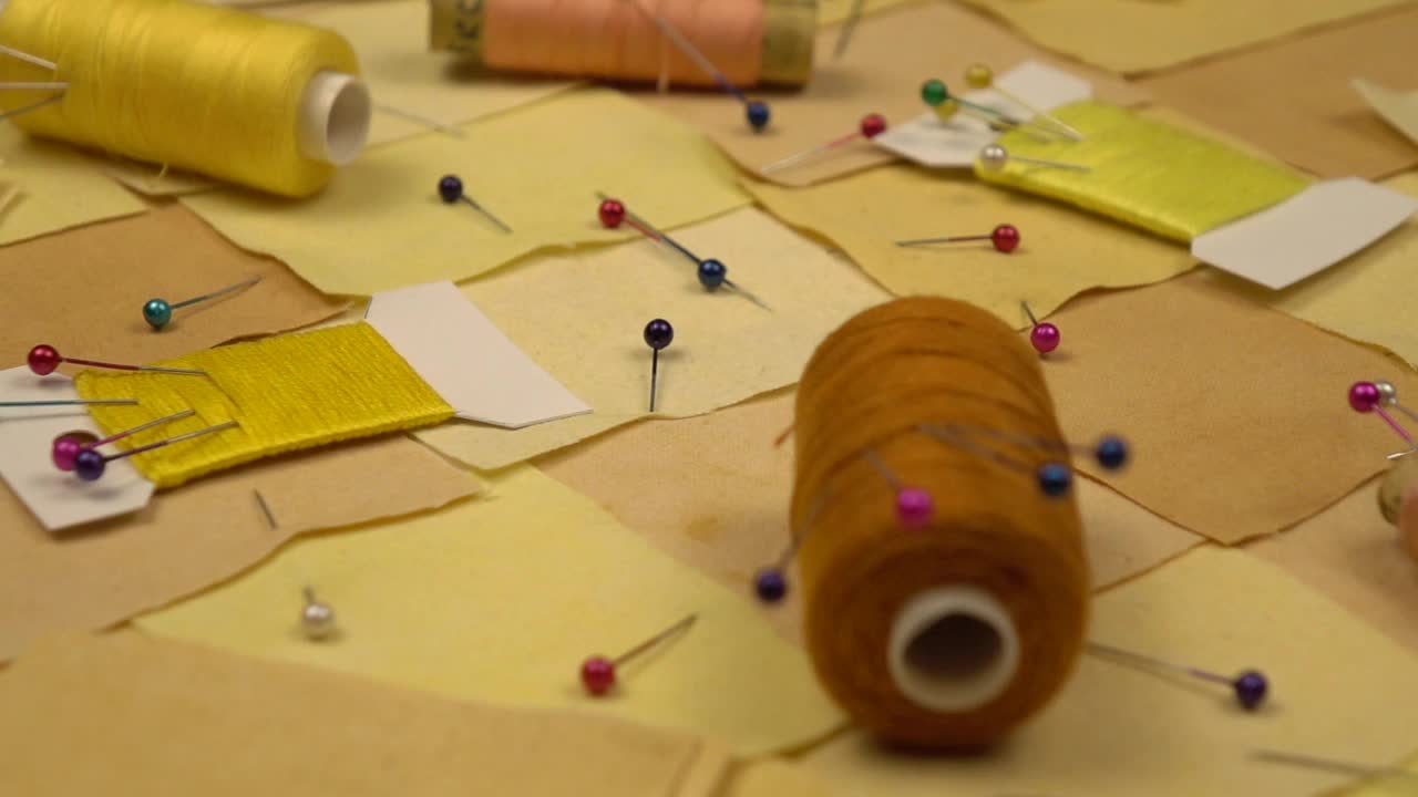 拼接缝纫的配件躺在拼接纺织品上，黄色调，慢动作视频素材