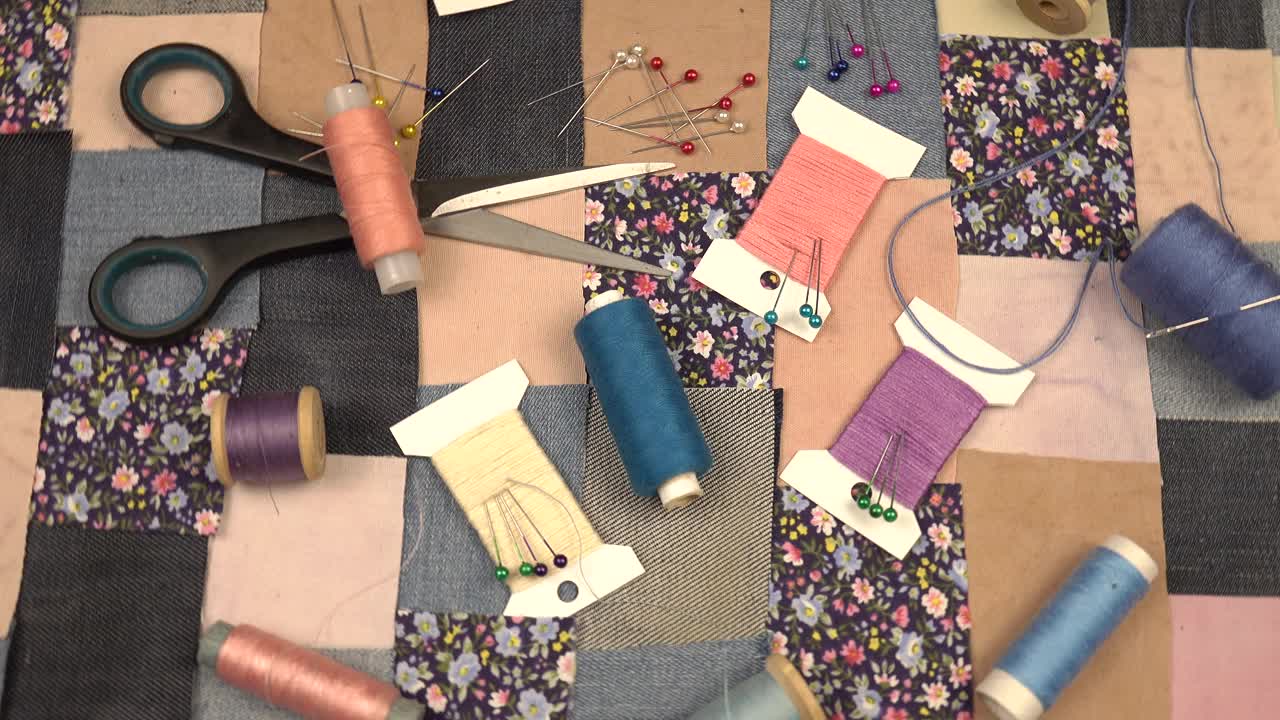 拼布缝纫的配件放在拼布纺织品上，上面有蓝色色调的印花棉布和牛仔布元素视频素材