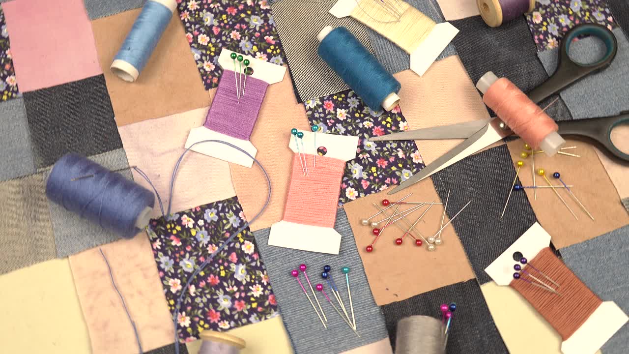 拼布缝纫的配件放在拼布纺织品上，上面有蓝色色调的印花棉布和牛仔布元素视频素材