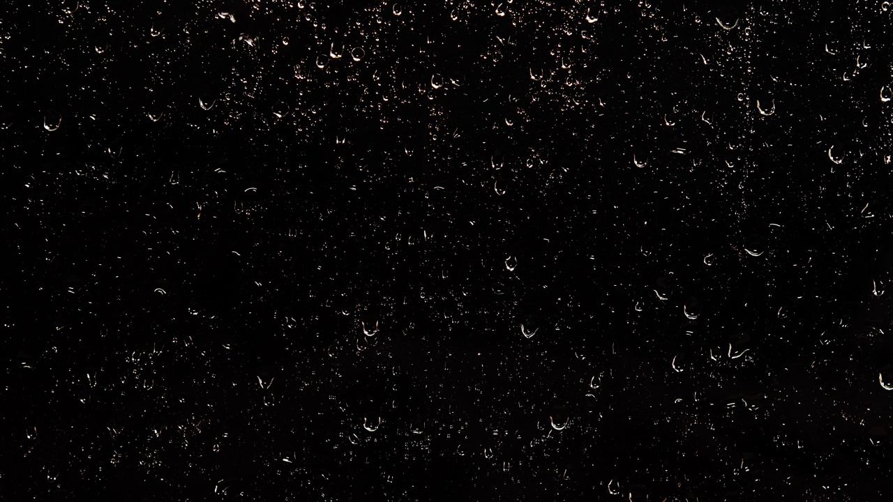 夜雨的水珠顺着黑色的玻璃流下来视频素材