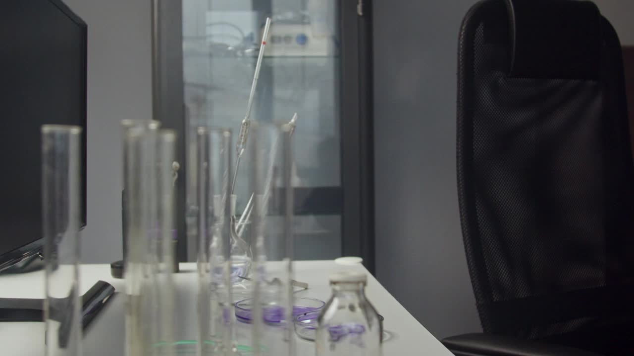 一名戴着防护面具的男子在实验室里进行化学实验。摄像机移动视频下载